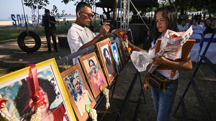 A woman places portraits of her relatives at the Ban Nam Khem Tsunami Memorial Park in southern Thai province of Phang Nga on December 26, 2024.