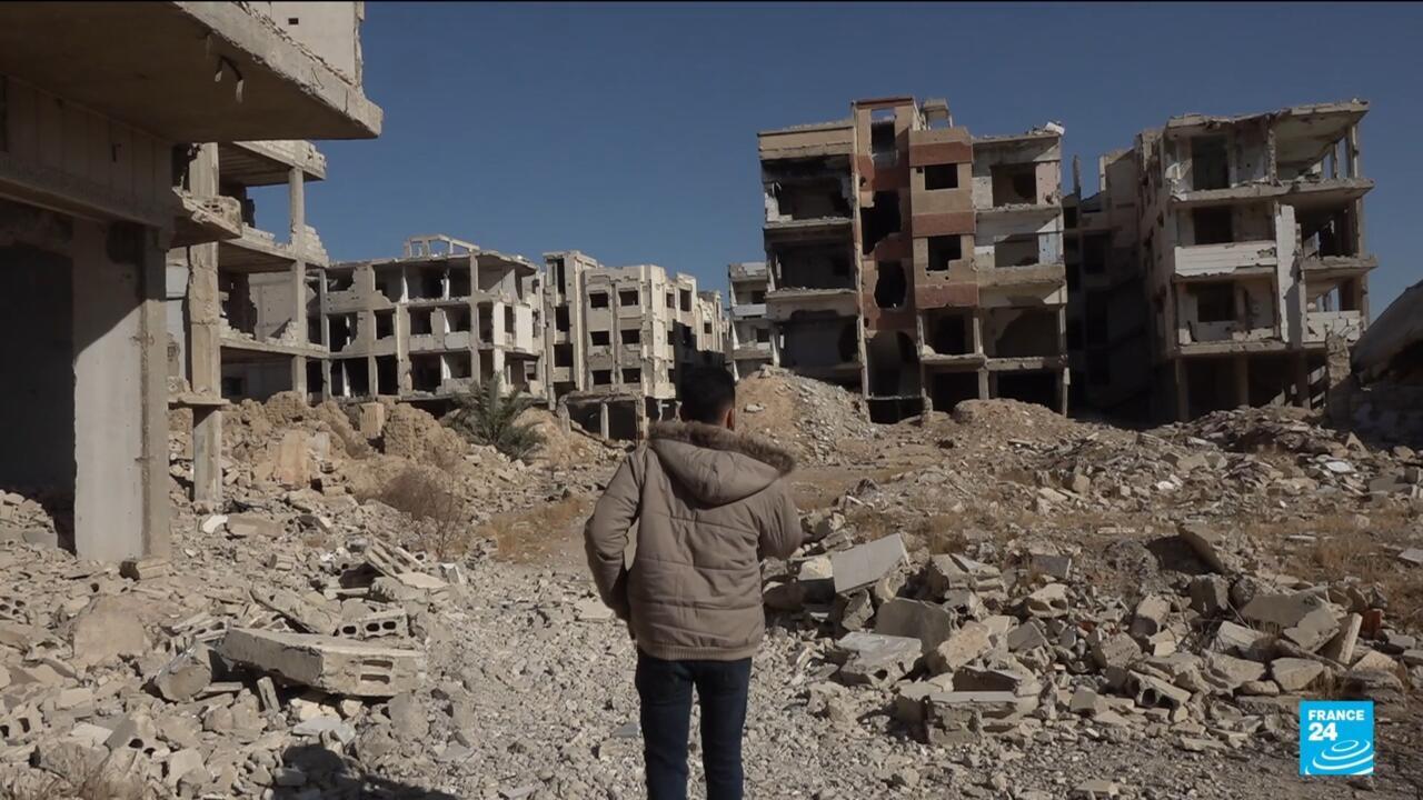 Ayham el Zaw stands in the bombed-+out ruins of Jubar, Syria.